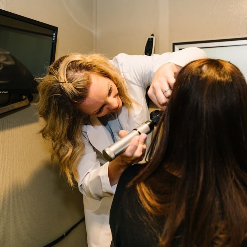 A photo of an audiologist checking a patient's ear